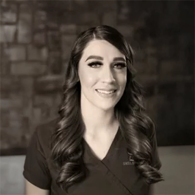 Danielle smiling in front of a brick wall.