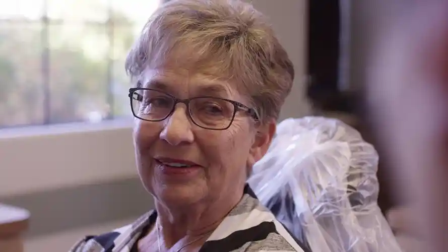Jane smiling with short hair and glasses.