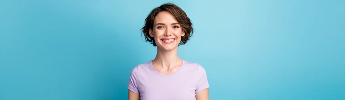 Dentist Avondale AZ Sedation Dentistry A girl with short hair smiling in front of a blue wall.