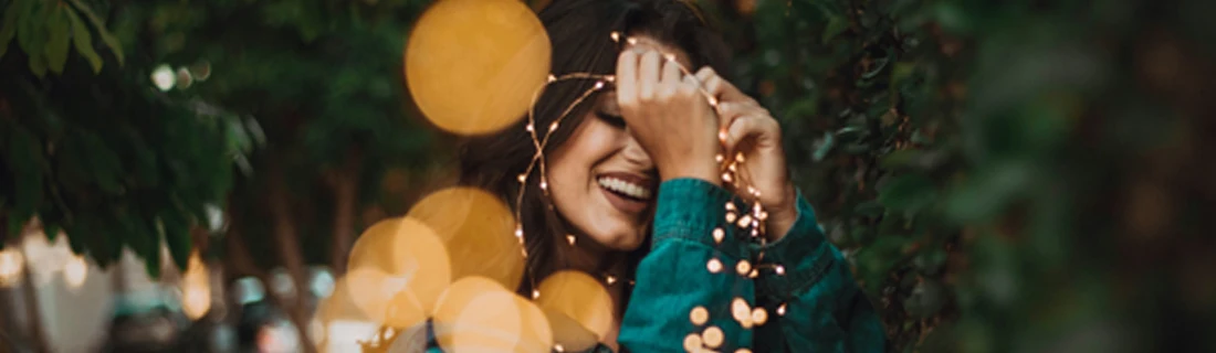Dentist Avondale AZ Smiling Woman With Lights A woman smiling while holding twinkle lights.
